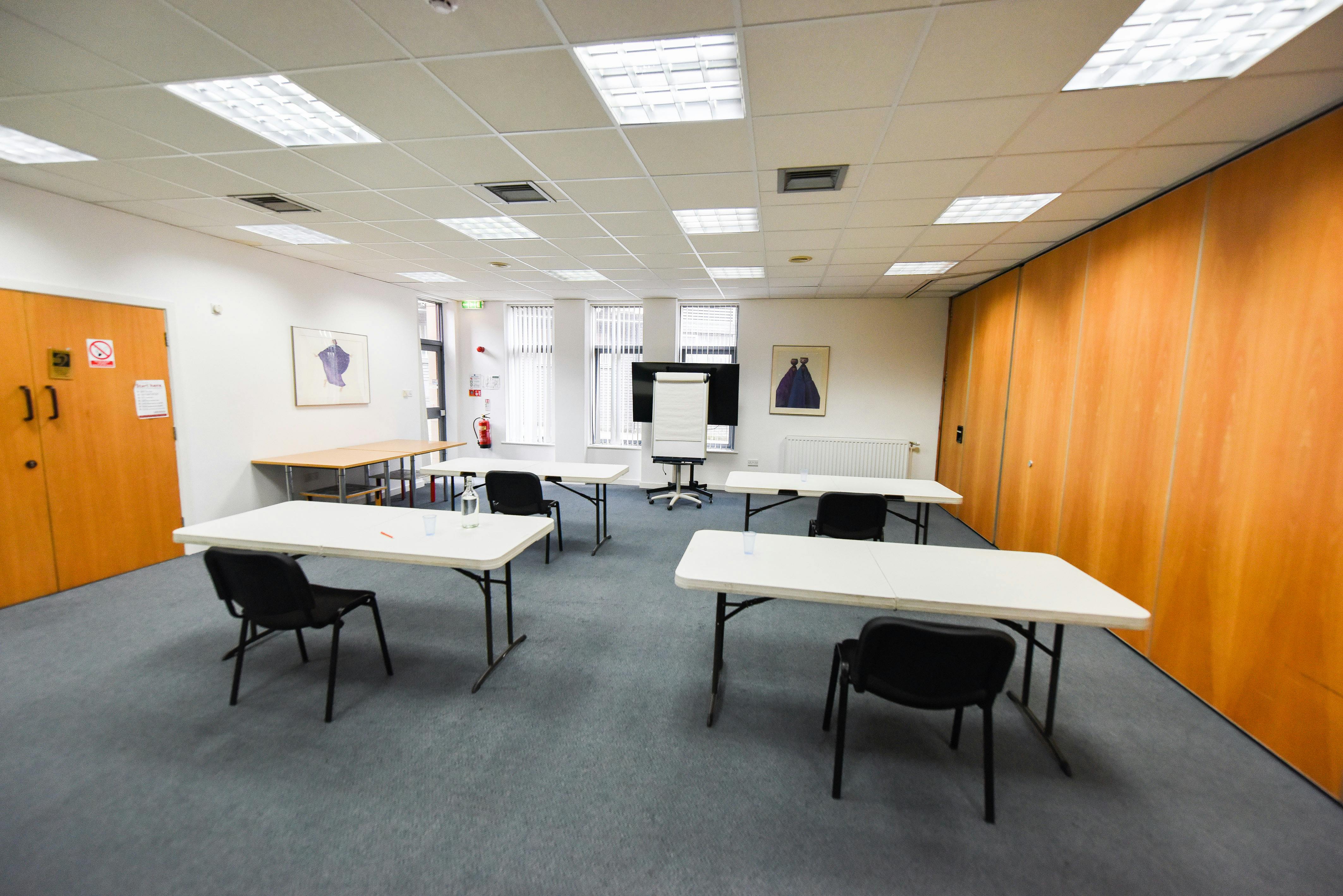 Versatile seminar room with natural light, ideal for workshops and brainstorming sessions.