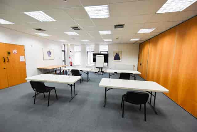 Versatile seminar room with natural light, ideal for workshops and brainstorming sessions.
