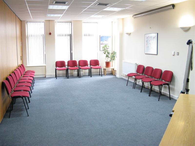 Versatile meeting space with red chairs, ideal for workshops and discussions.