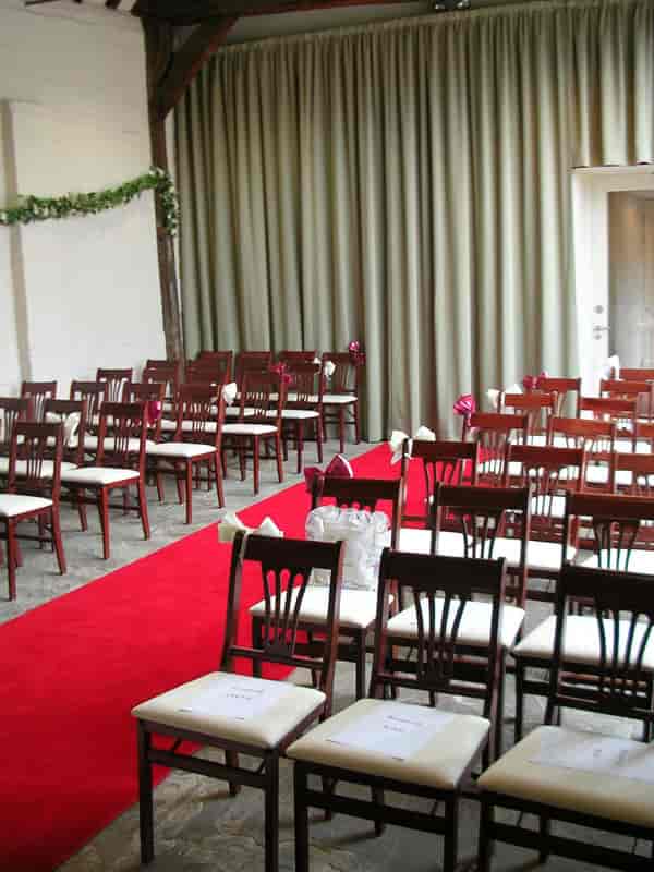 Elegant wedding ceremony space in Blakesley Hall with wooden chairs and red carpet.