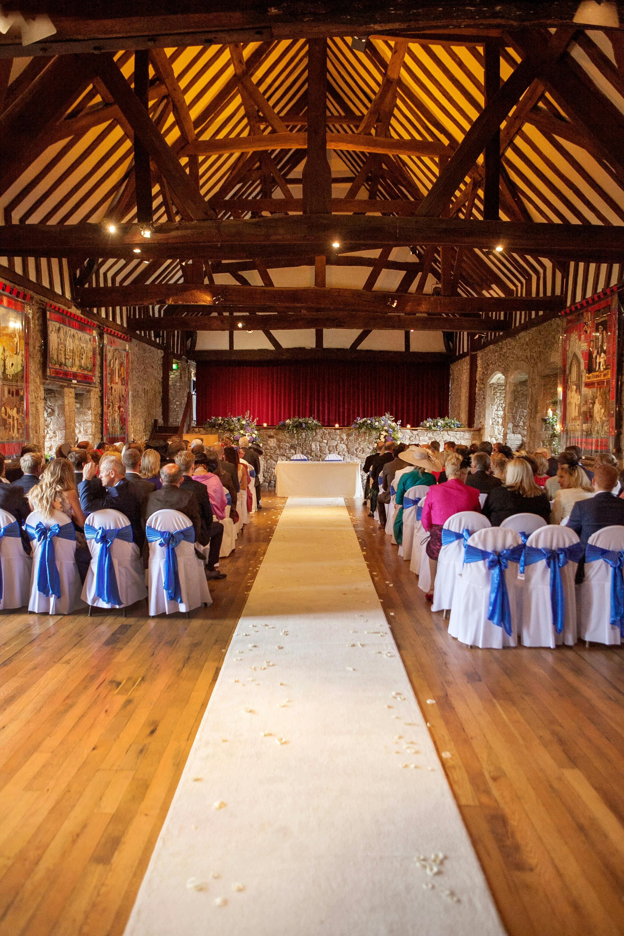 Rustic wedding ceremony at Domus Beaulieu with blue-sashed seating and petal-lined aisle.