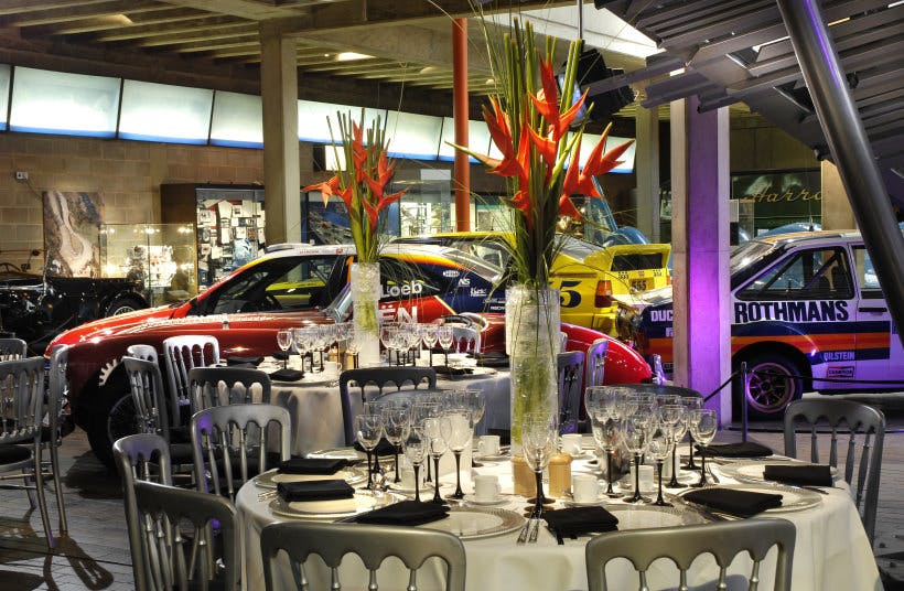 Elegant event space at National Motor Museum with vintage cars and floral arrangements.