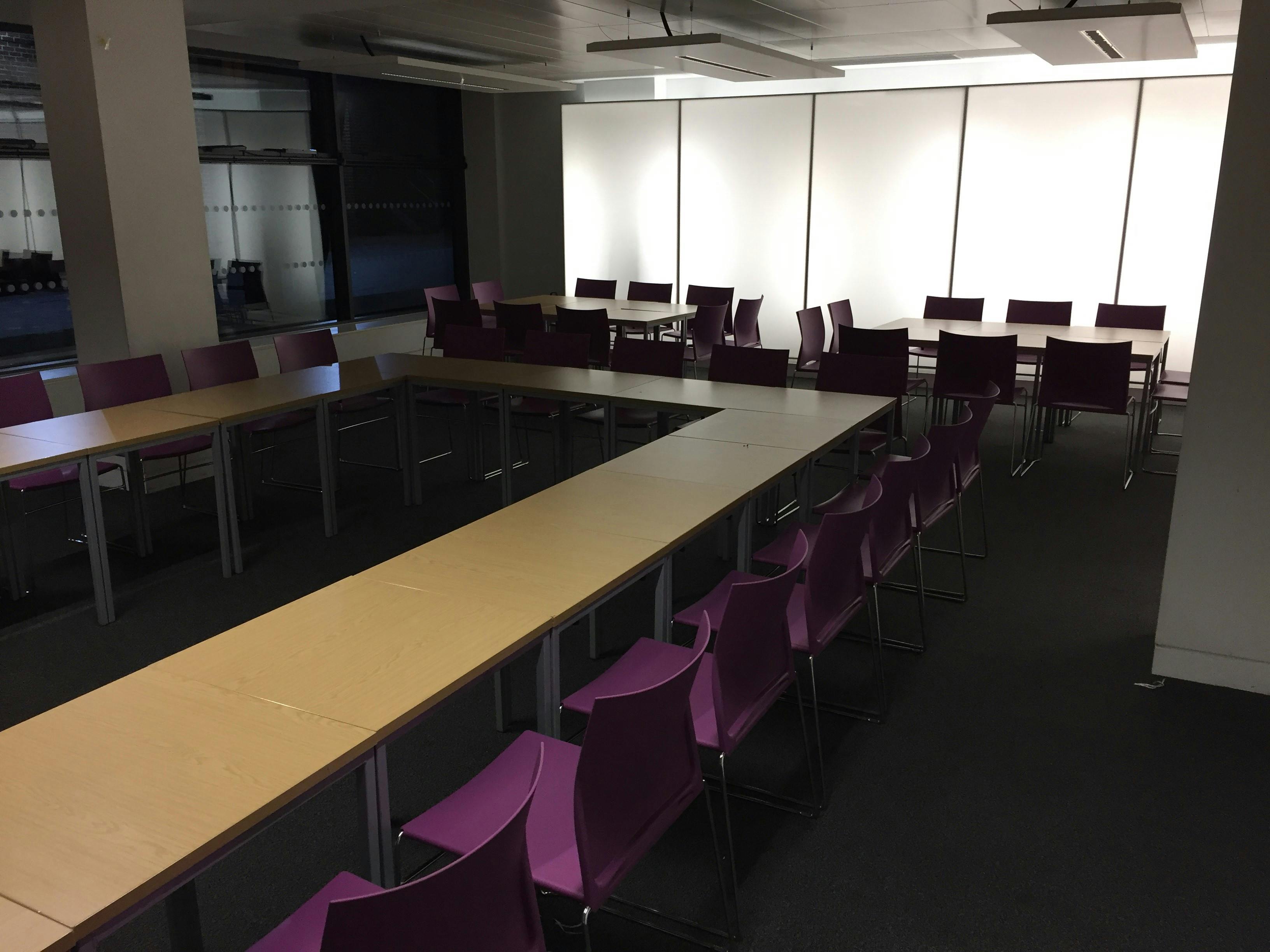 Versatile meeting space with modular tables and purple chairs at Queen Mary University.