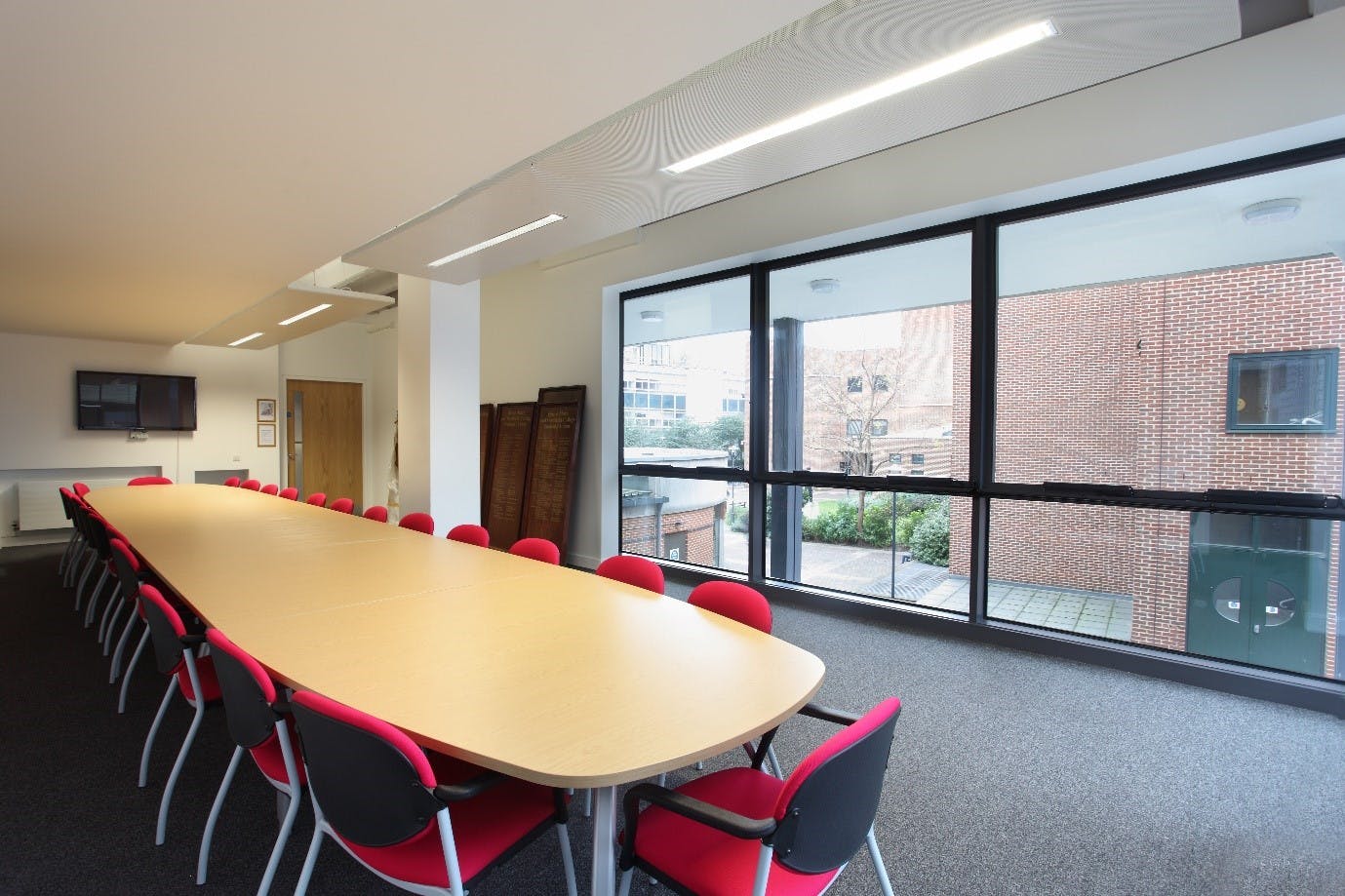 Modern conference room with oval table and red chairs at Queen Mary University.