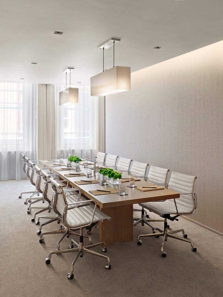 Modern meeting room with wooden table and ergonomic chairs at The London EDITION.