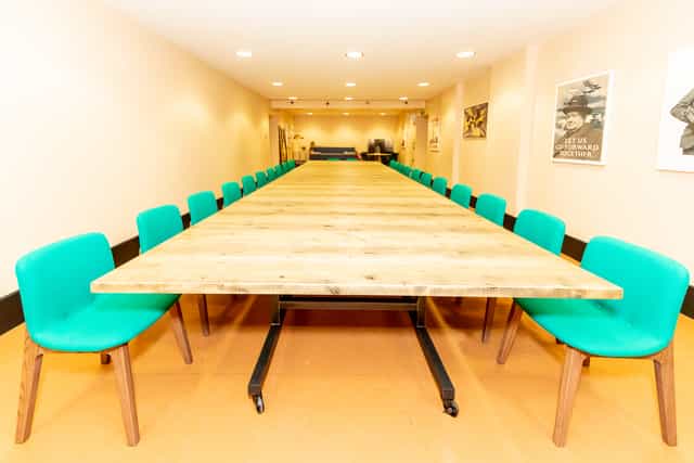 Spacious Churchill War Rooms meeting room with wooden table and teal chairs for workshops.
