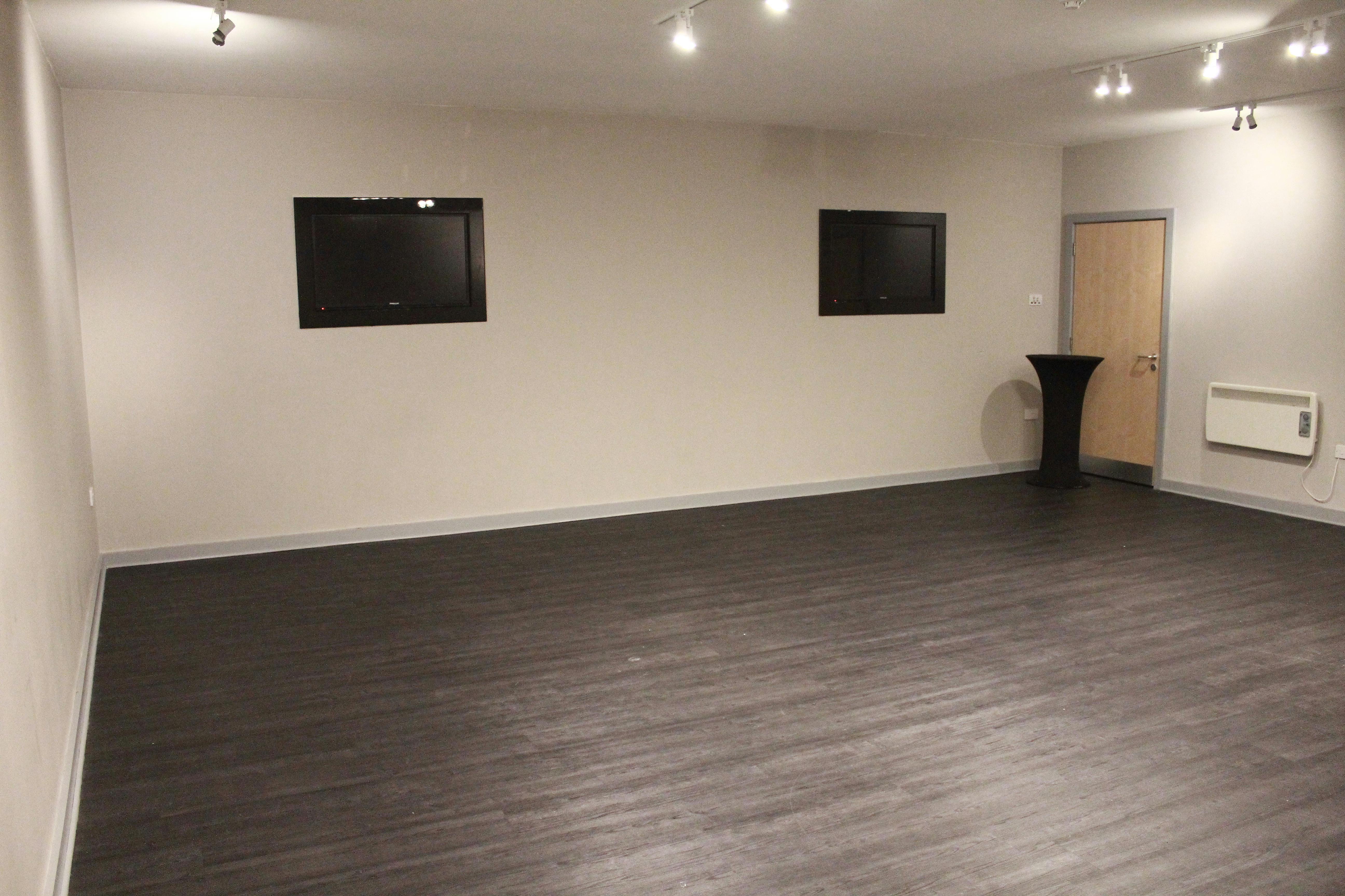 Versatile event space with mounted screens, ideal for corporate meetings and social gatherings.