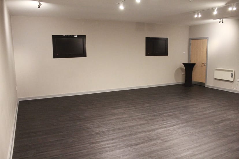 Versatile event space with mounted screens, ideal for corporate meetings and social gatherings.