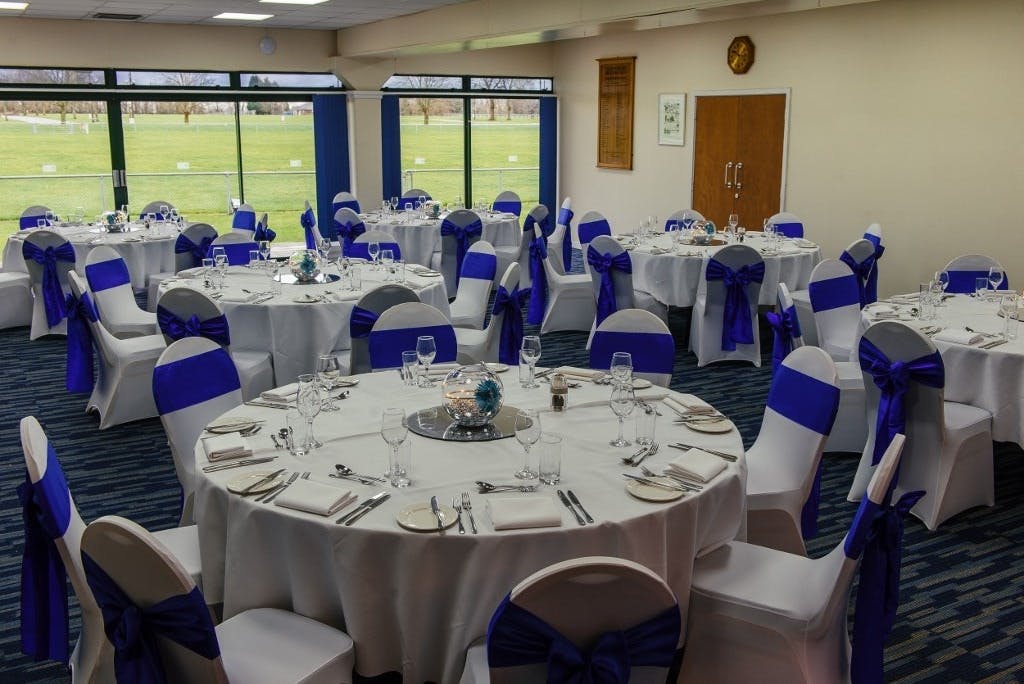 Kleinwort Room set for a formal event with elegant tables and blue chair sashes.