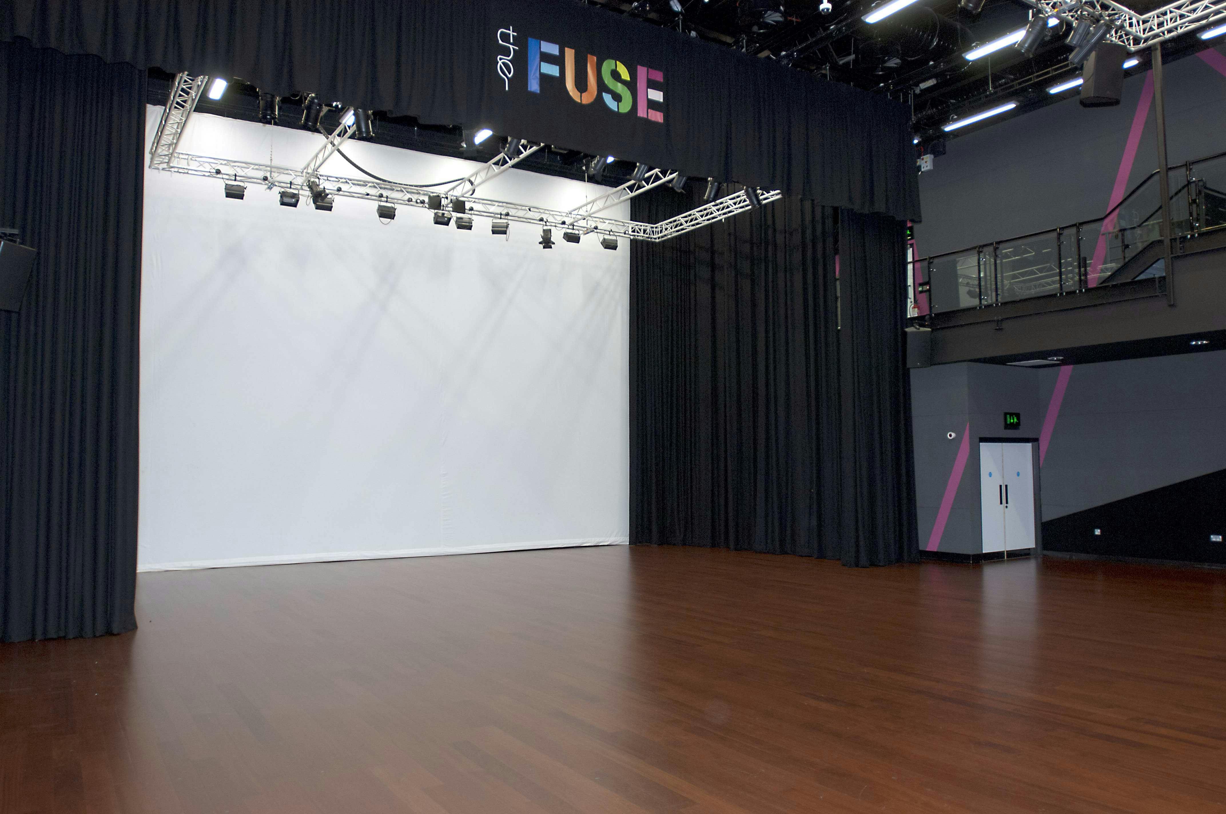 Versatile auditorium with wooden floor, ideal for conferences and workshops.