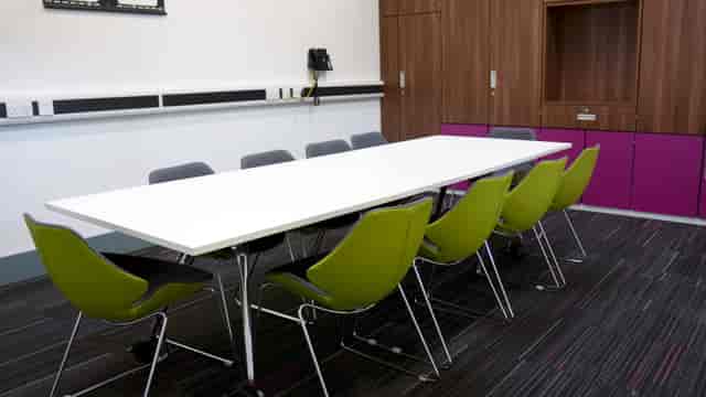 Modern boardroom with white table and green chairs, perfect for creative meetings.