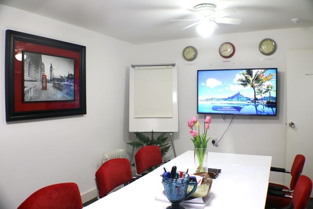 Modern meeting room with large white table and red chairs for professional gatherings.