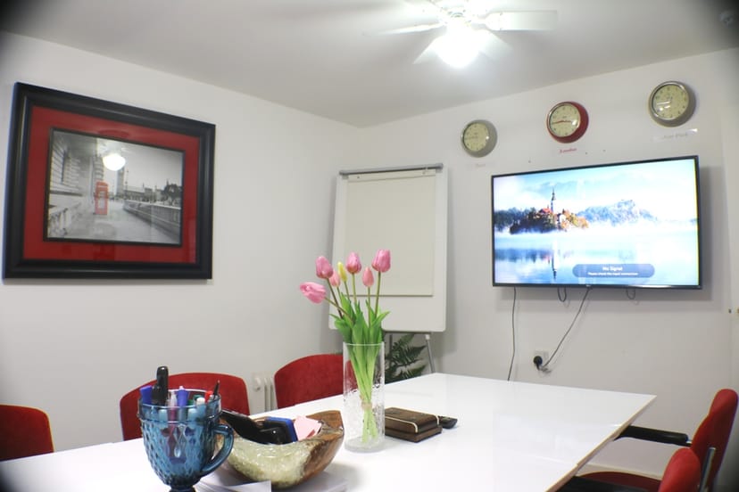 Modern meeting room with large white table and red chairs near Liverpool St for conferences.