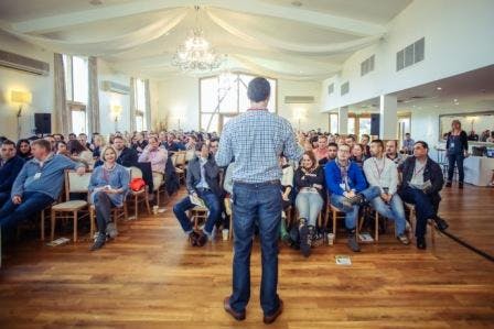 Engaged audience at Mythe Barn conference with natural light and elegant decor.