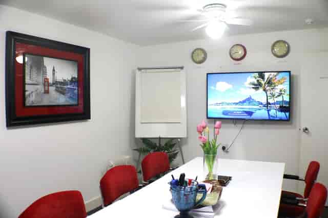 Modern meeting room with large white table and red chairs for corporate events.