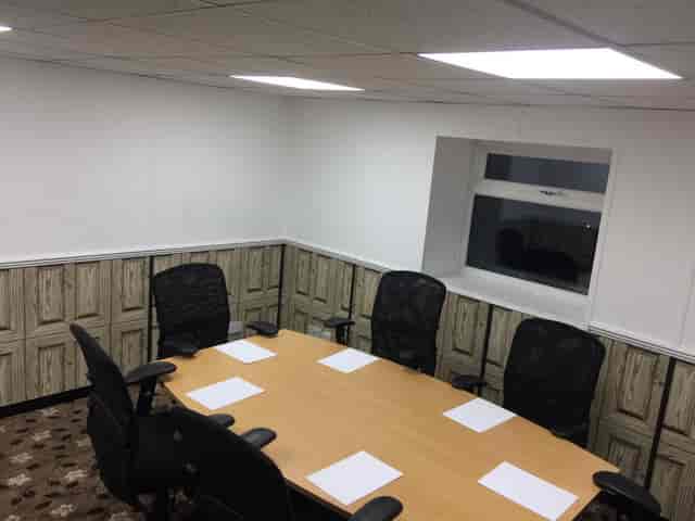 Well-lit meeting room with round table and ergonomic chairs for productive discussions.