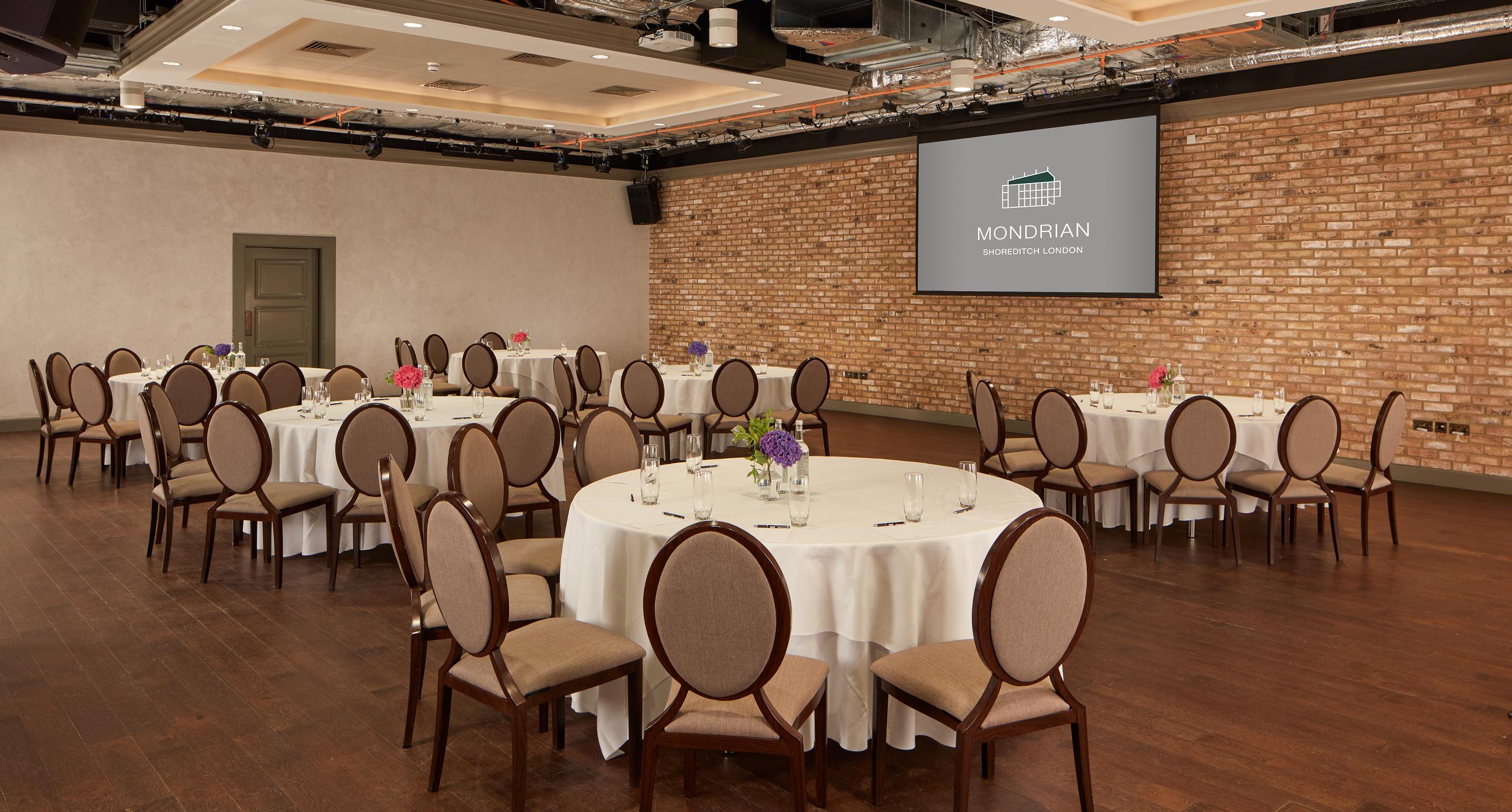 The Ballroom at Virgin Hotels London: elegant corporate event space with floral centerpieces.