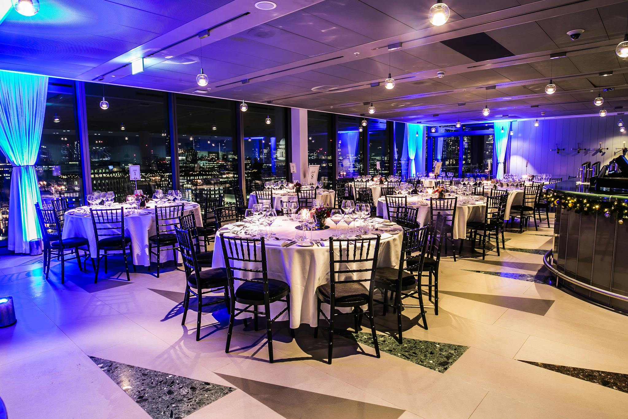 Elegant event space with round tables and skyline view for corporate dinners.