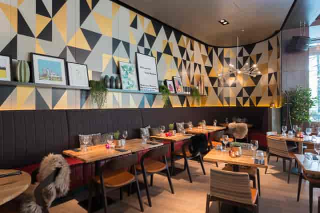 Modern restaurant venue with geometric wall, ideal for corporate events and gatherings.