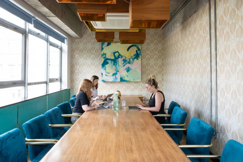 Modern meeting room with wooden table and teal chairs, perfect for team brainstorming sessions.