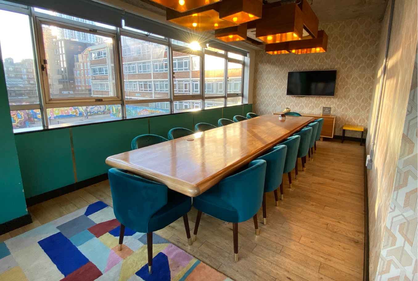 Modern meeting room with wooden table and teal chairs, perfect for workshops and team meetings.