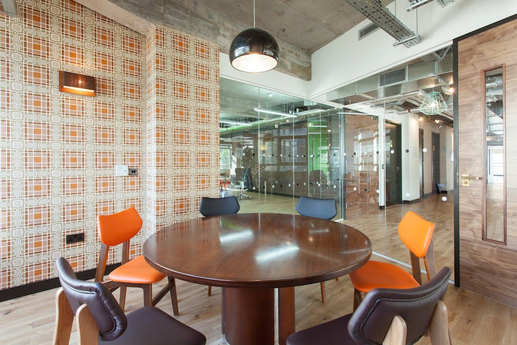 Modern meeting room with round wooden table, ideal for brainstorming sessions.