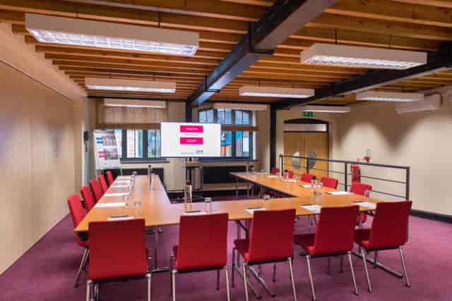 Faraday Room at IET Birmingham: modern meeting space with red chairs for workshops.