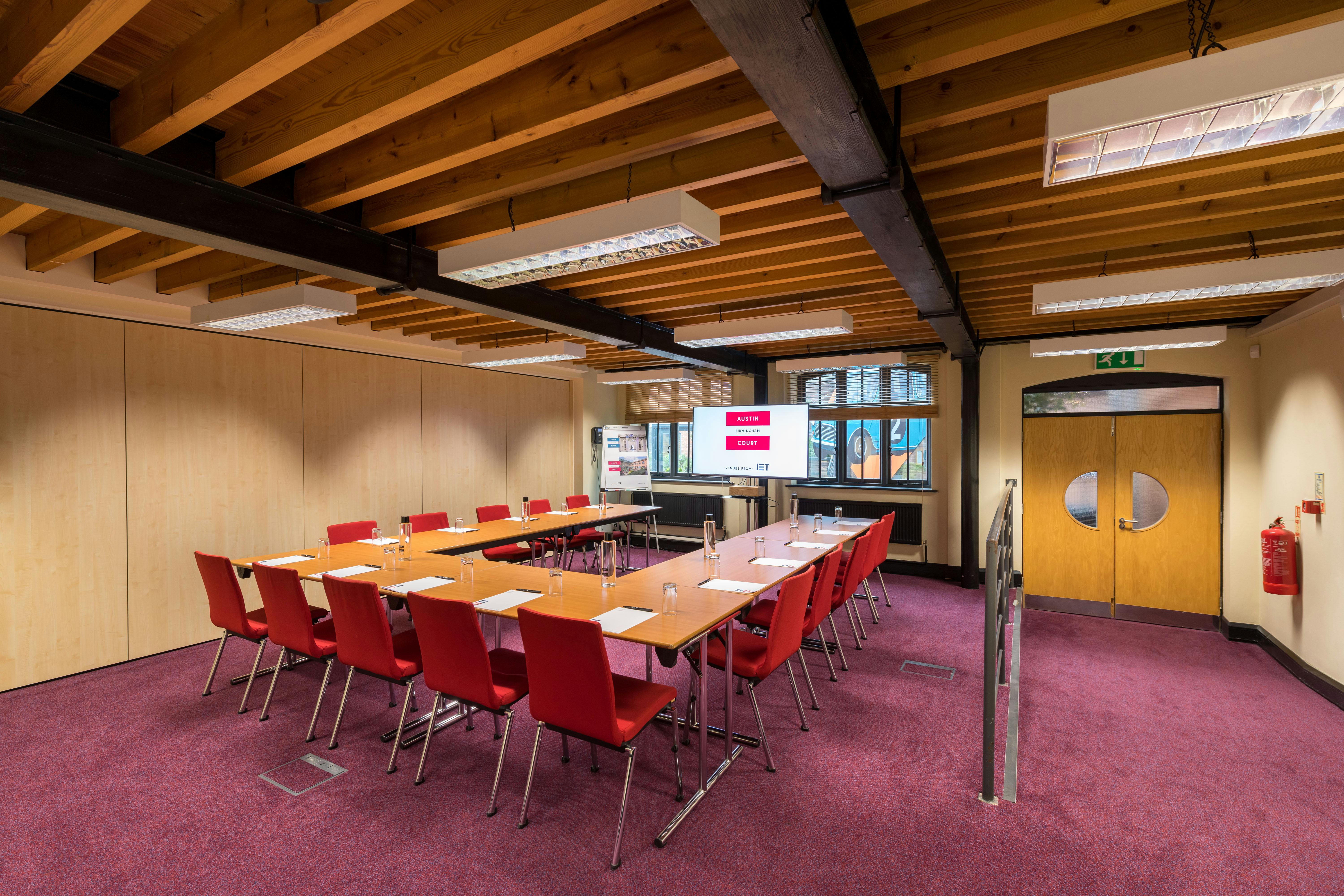 Faraday Room at IET Birmingham: modern meeting space with red chairs for workshops.