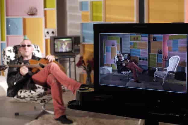 Musician in colorful TV studio setup for engaging virtual event presentation.