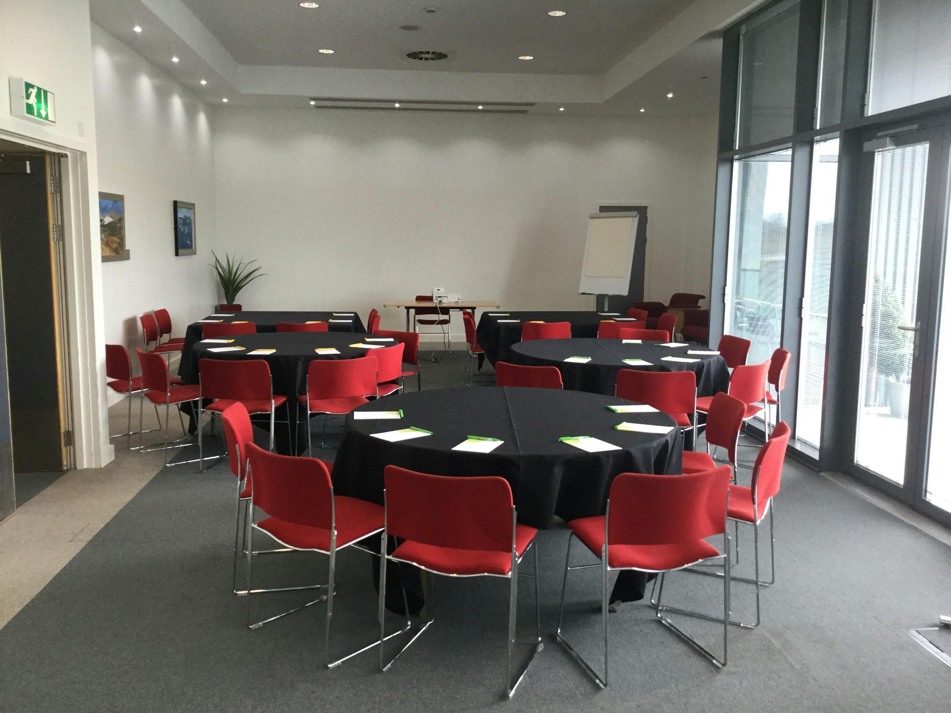 Airside Suite at IWM Duxford, featuring round tables and red chairs for workshops.