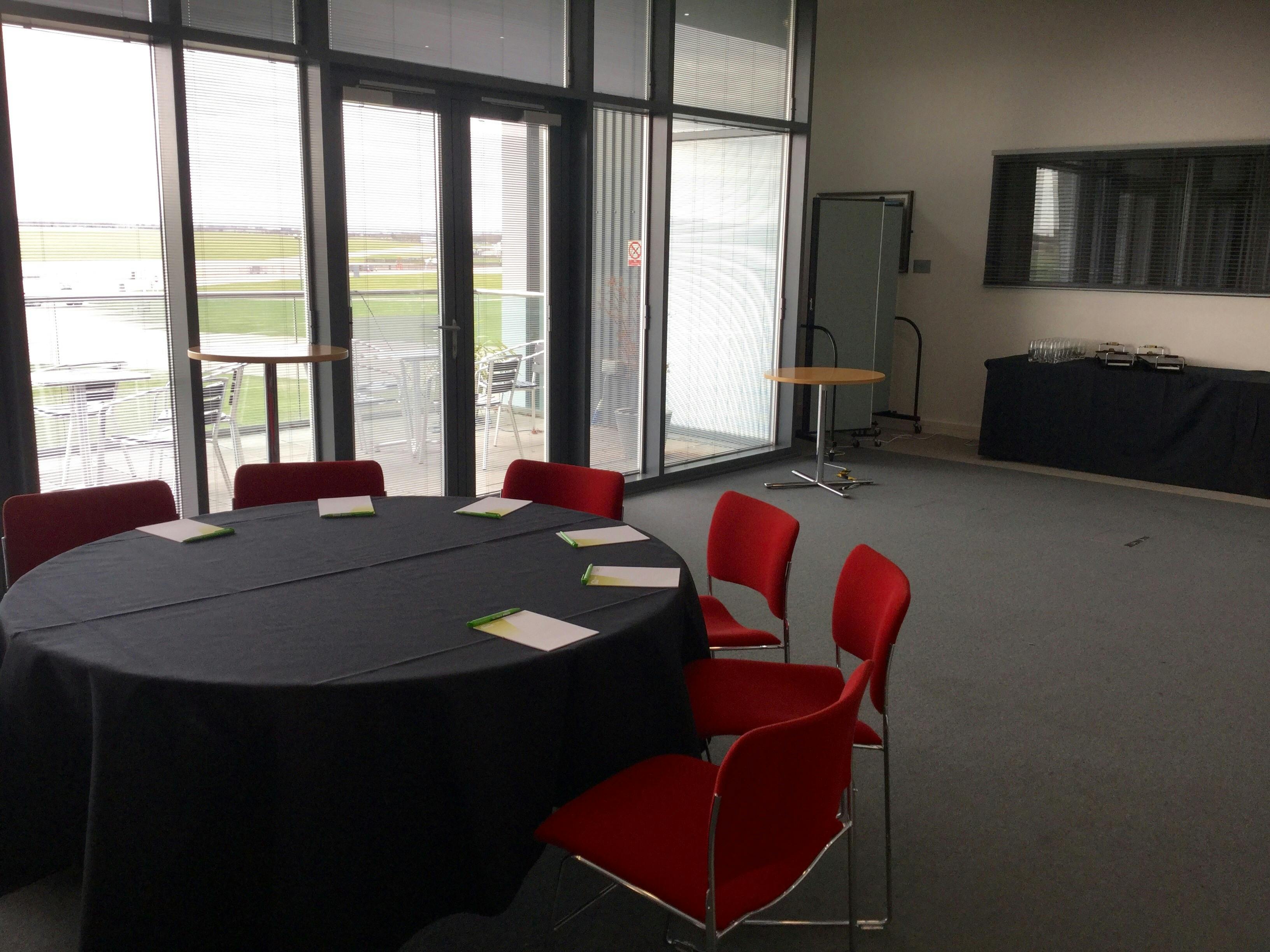 Airside Suite at IWM Duxford, round table meeting space with vibrant red chairs.