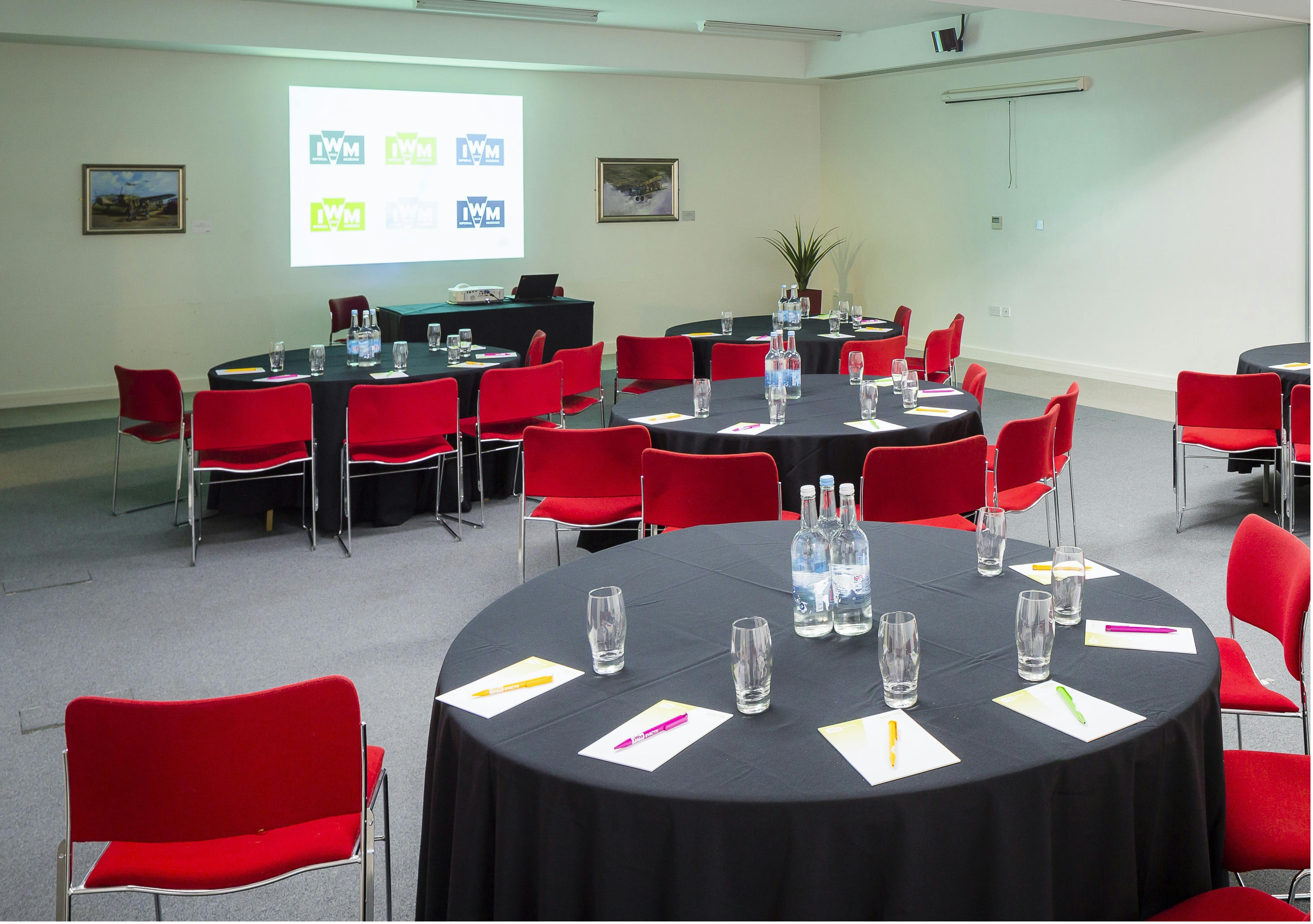 Concorde Suite meeting space with round tables, red chairs for corporate events.