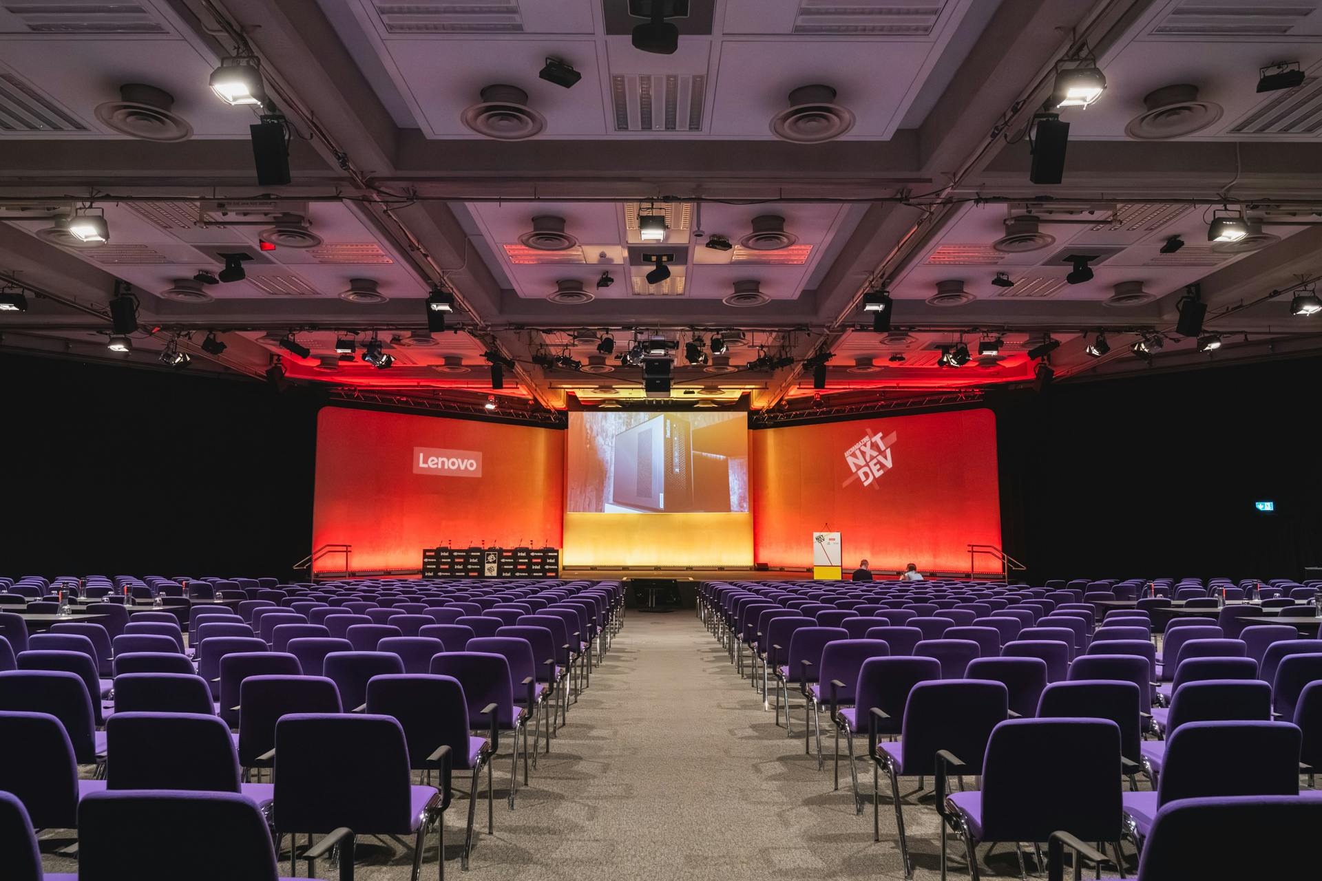 Conference space at QEII Centre with purple chairs and vibrant stage for corporate events.