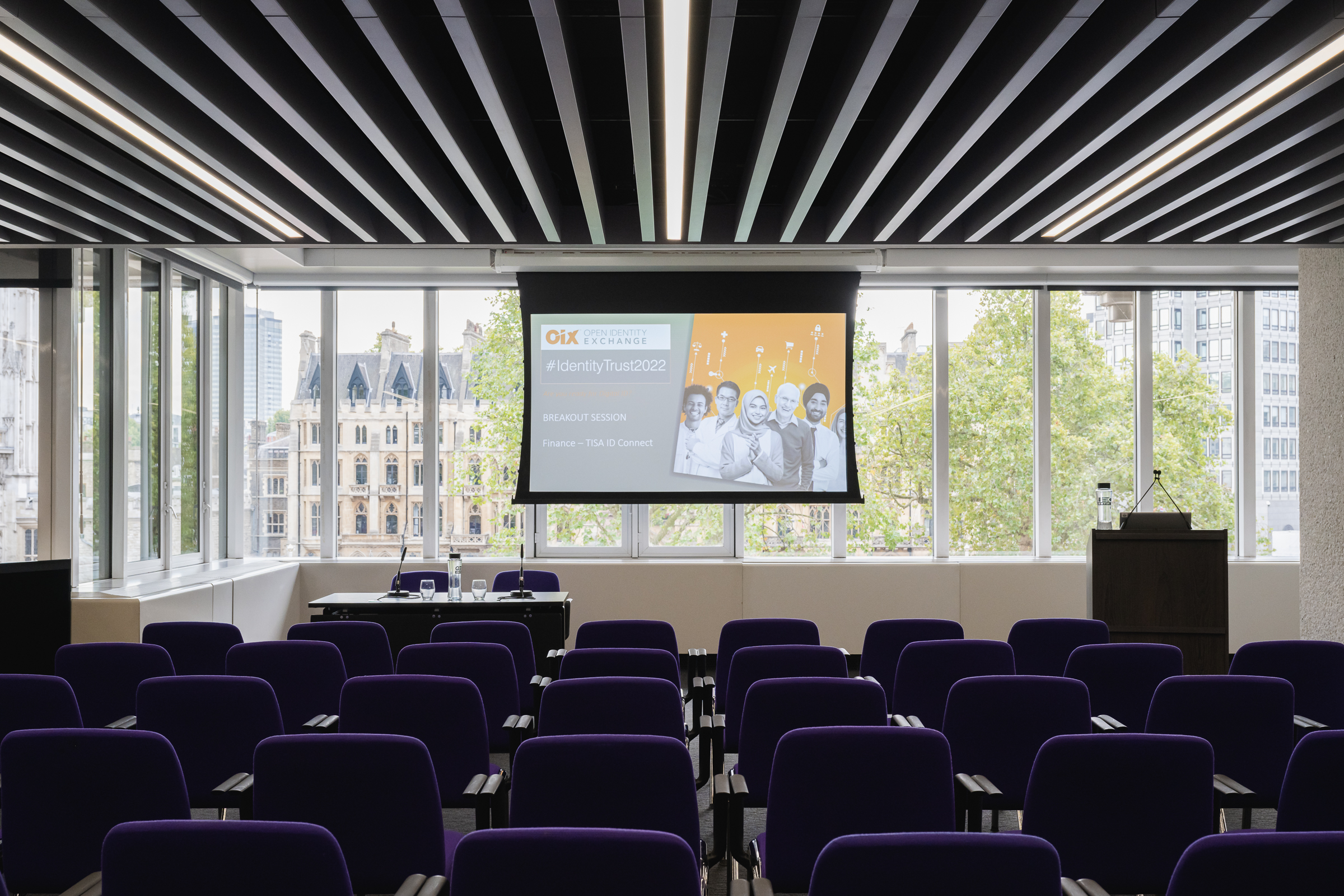 Olivier in modern QEII Centre meeting room with purple chairs for a conference presentation. - Banner
