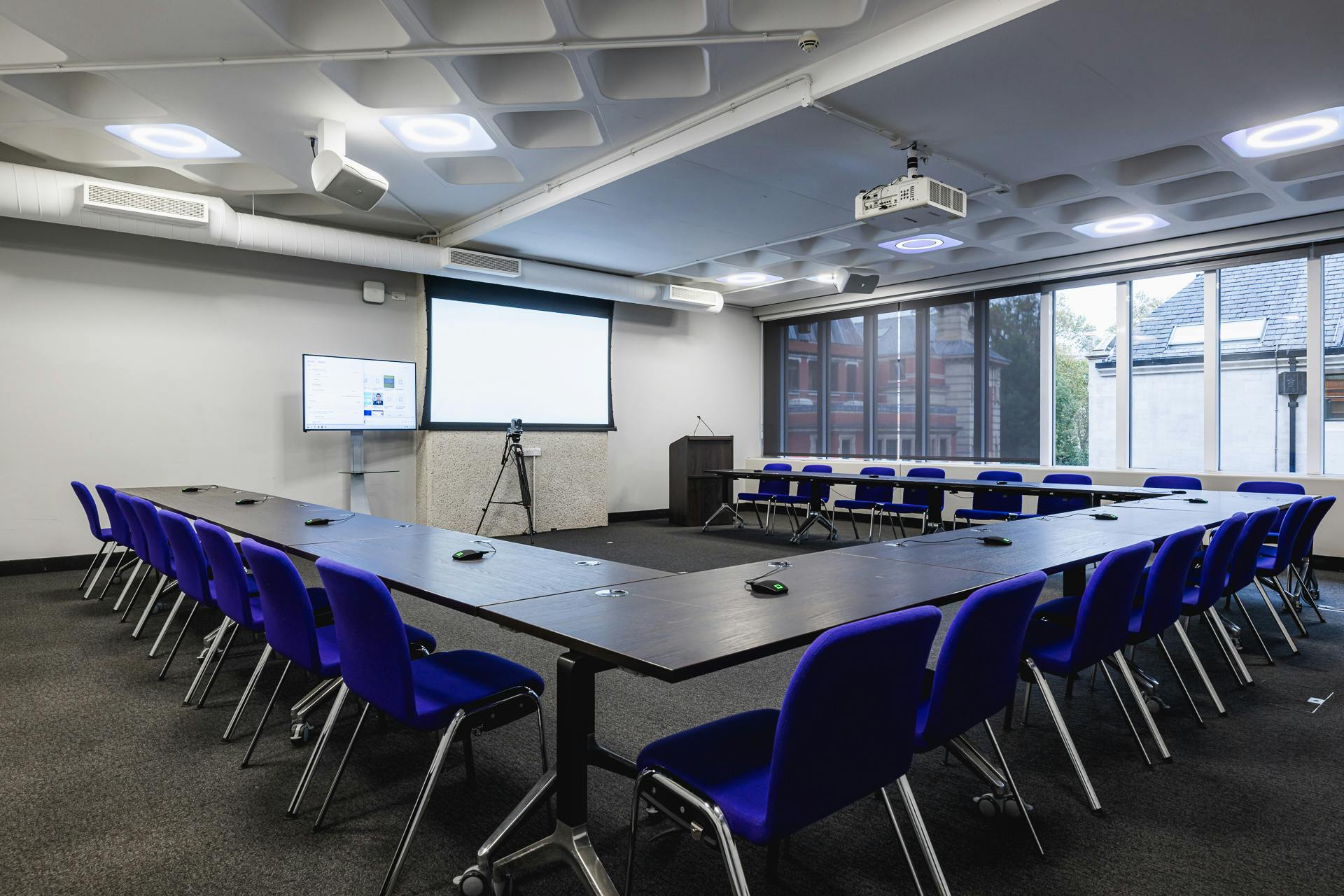 Modern meeting room at QEII Centre with U-shaped table, ideal for presentations and discussions.