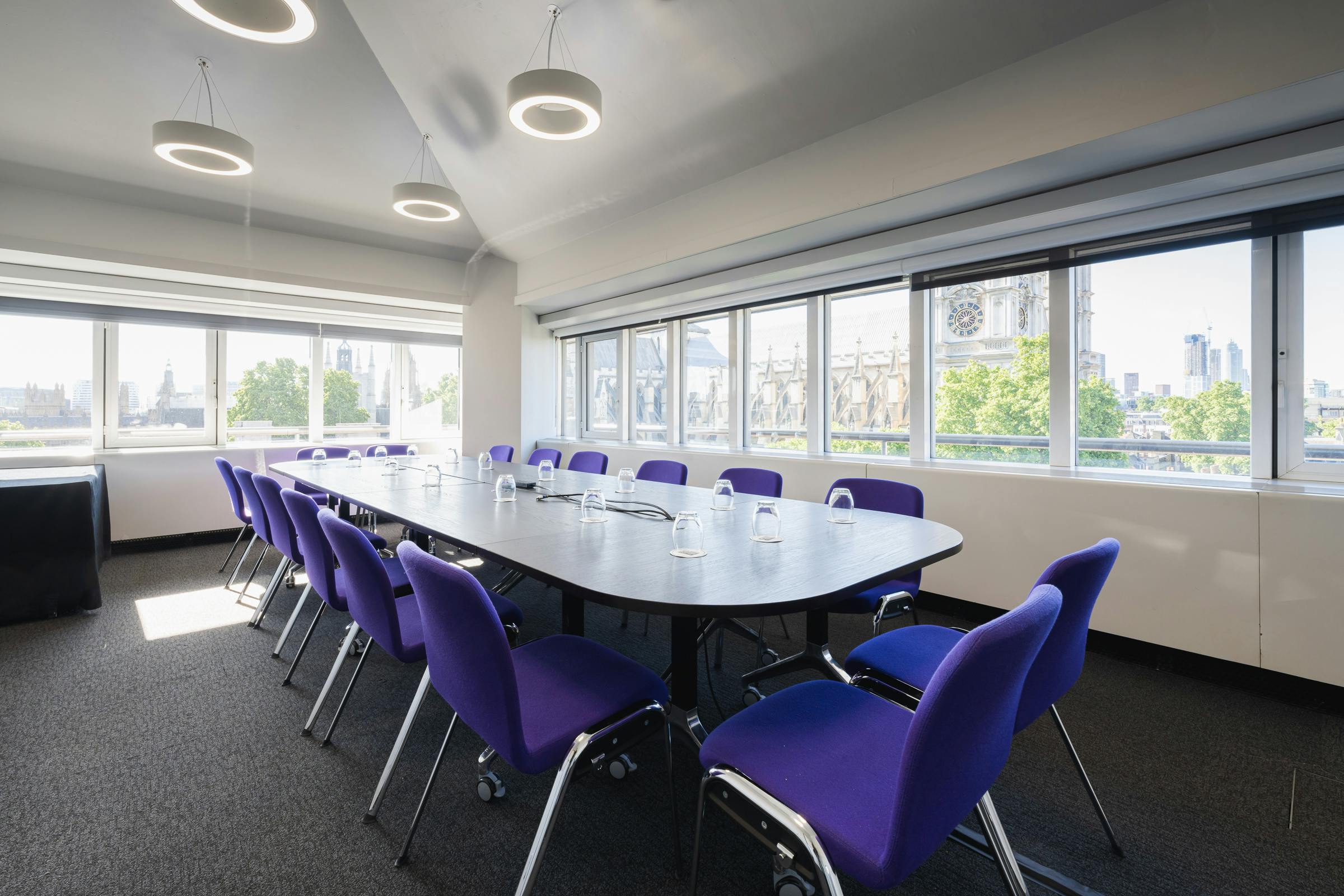 Modern meeting room with oval table and ergonomic purple chairs, ideal for workshops.