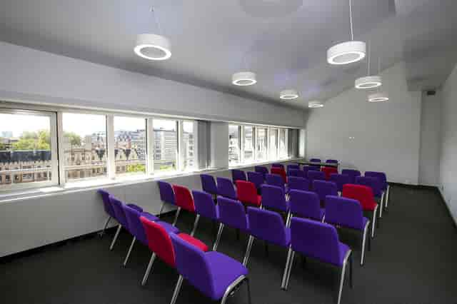 Modern meeting room in QEII Centre with colorful chairs, ideal for workshops and presentations.