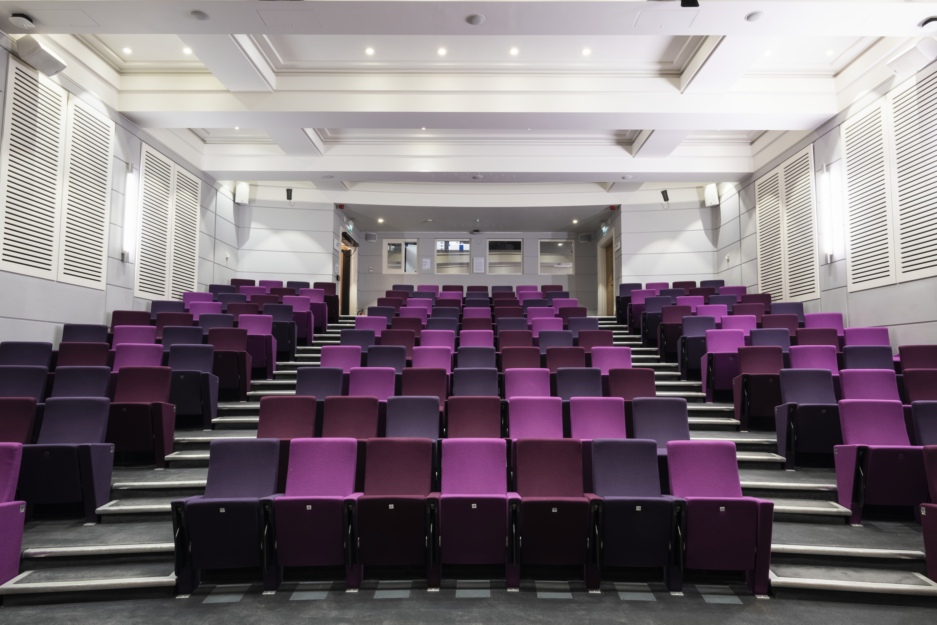 Henry Wellcome Auditorium with tiered purple seating for conferences and presentations. - Banner