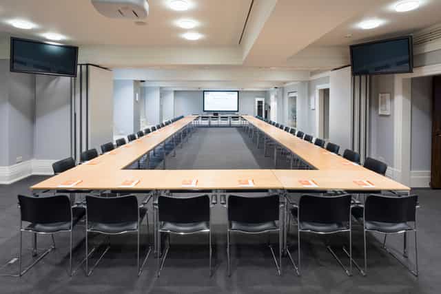 Franks & Steel Room U-shaped meeting setup with dual screens for collaborative discussions.