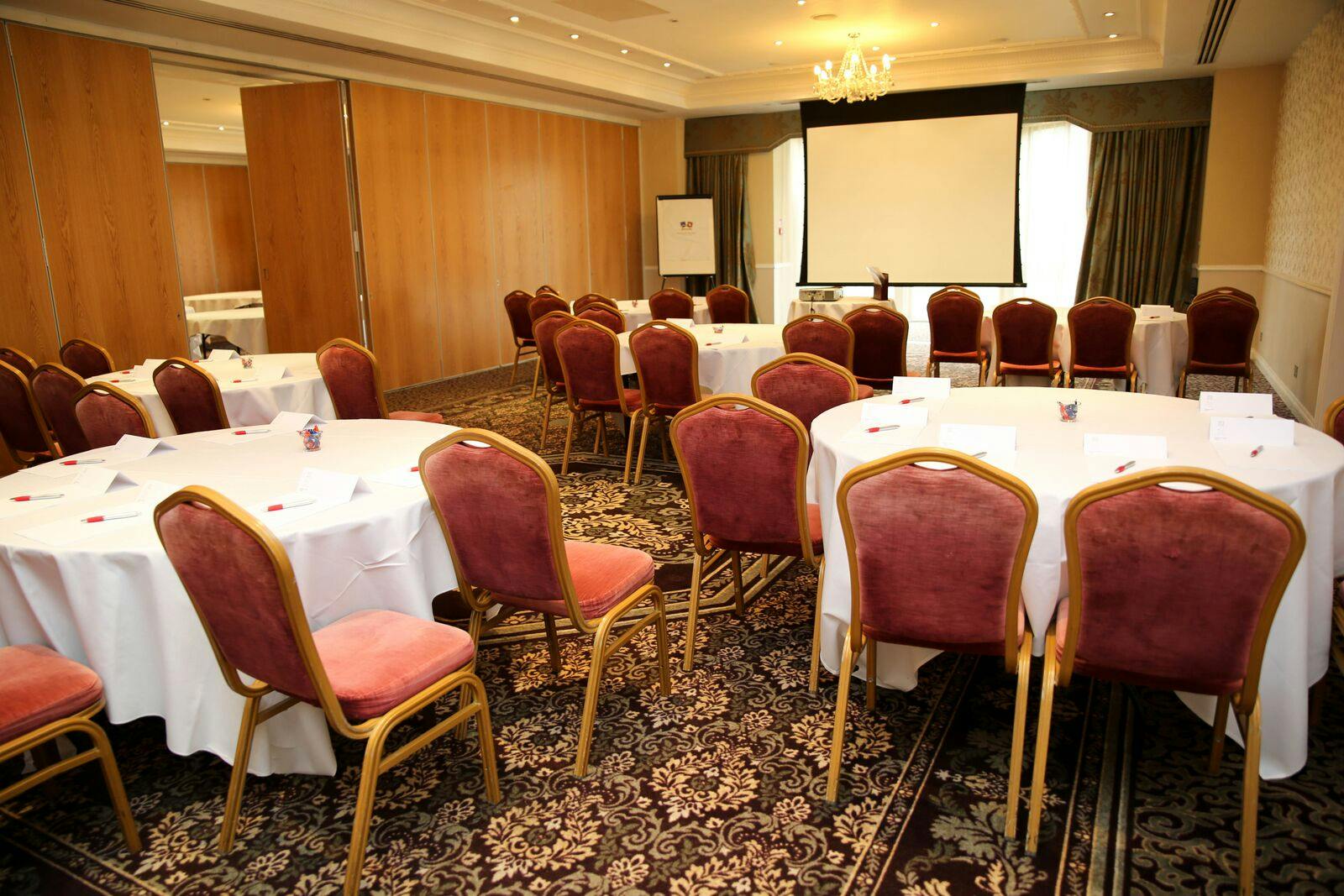 Aspley Suite at Shendish Manor Hotel, ideal for conferences with circular tables and projector.