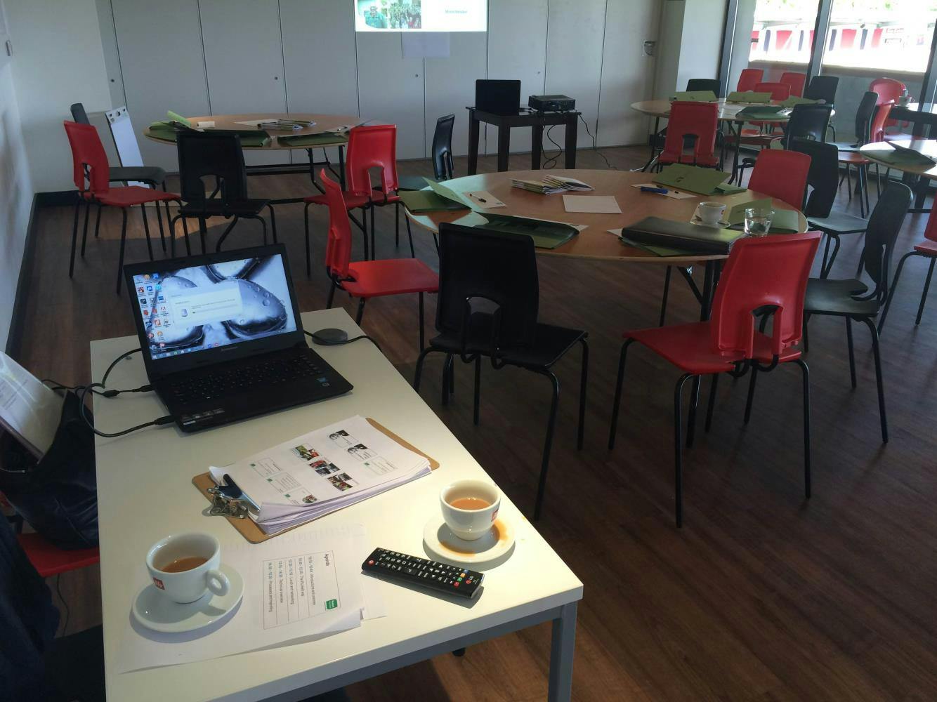 Classroom meeting space with round tables, red chairs for collaborative gatherings.