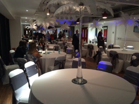 Stylish FC United function room set for elegant networking event with palm tree centerpieces.