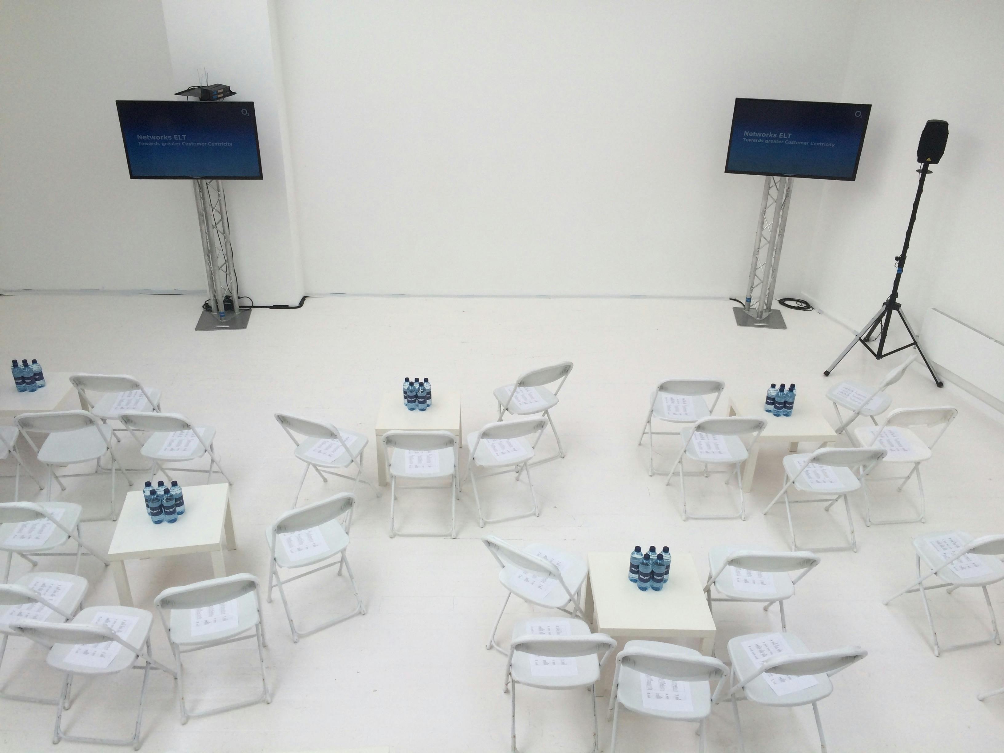 Minimalist loft event setup with white chairs, ideal for workshops and meetings.