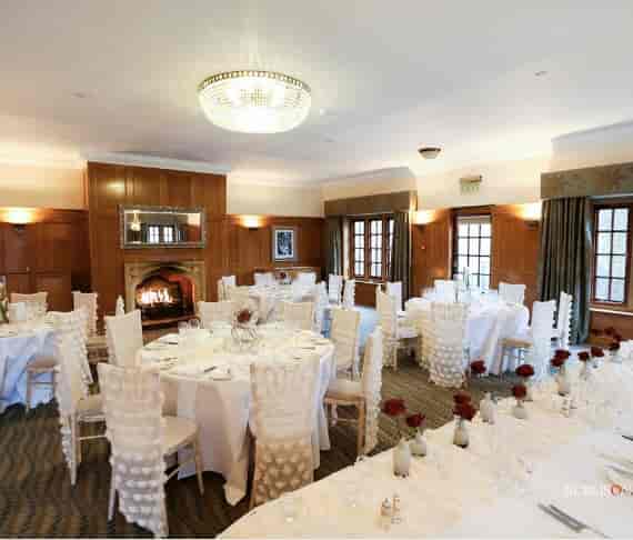Elegant banquet room with white linens and red roses, perfect for weddings and corporate events.