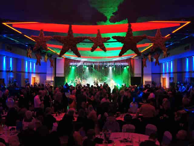 Vibrant gala at The Riverside venue with elegant decor and live performance stage.