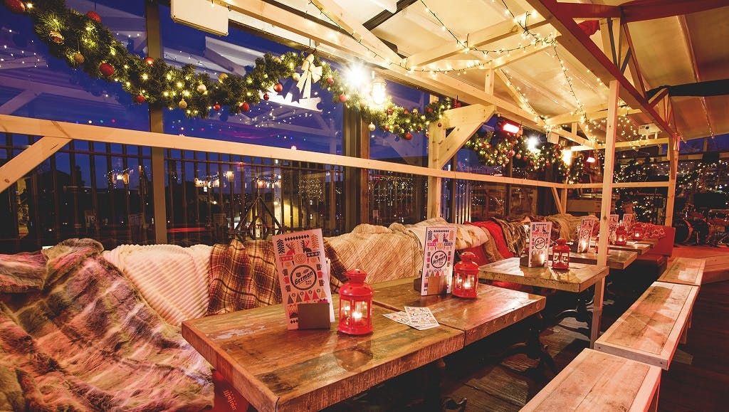 Cozy rooftop terrace with warm lighting, perfect for holiday parties and gatherings.