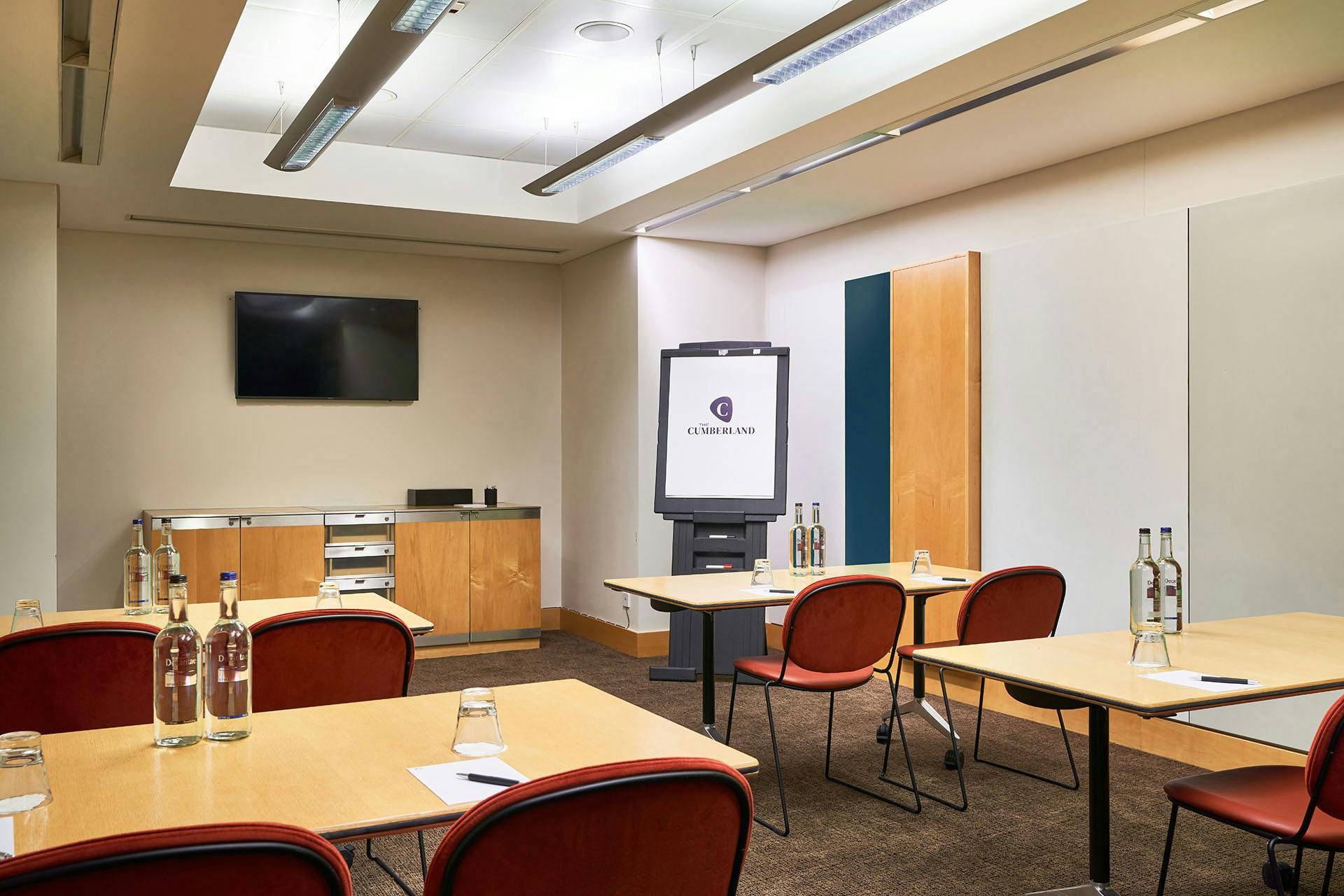 Modern meeting room at The Cumberland Hotel with natural light and presentation screen.