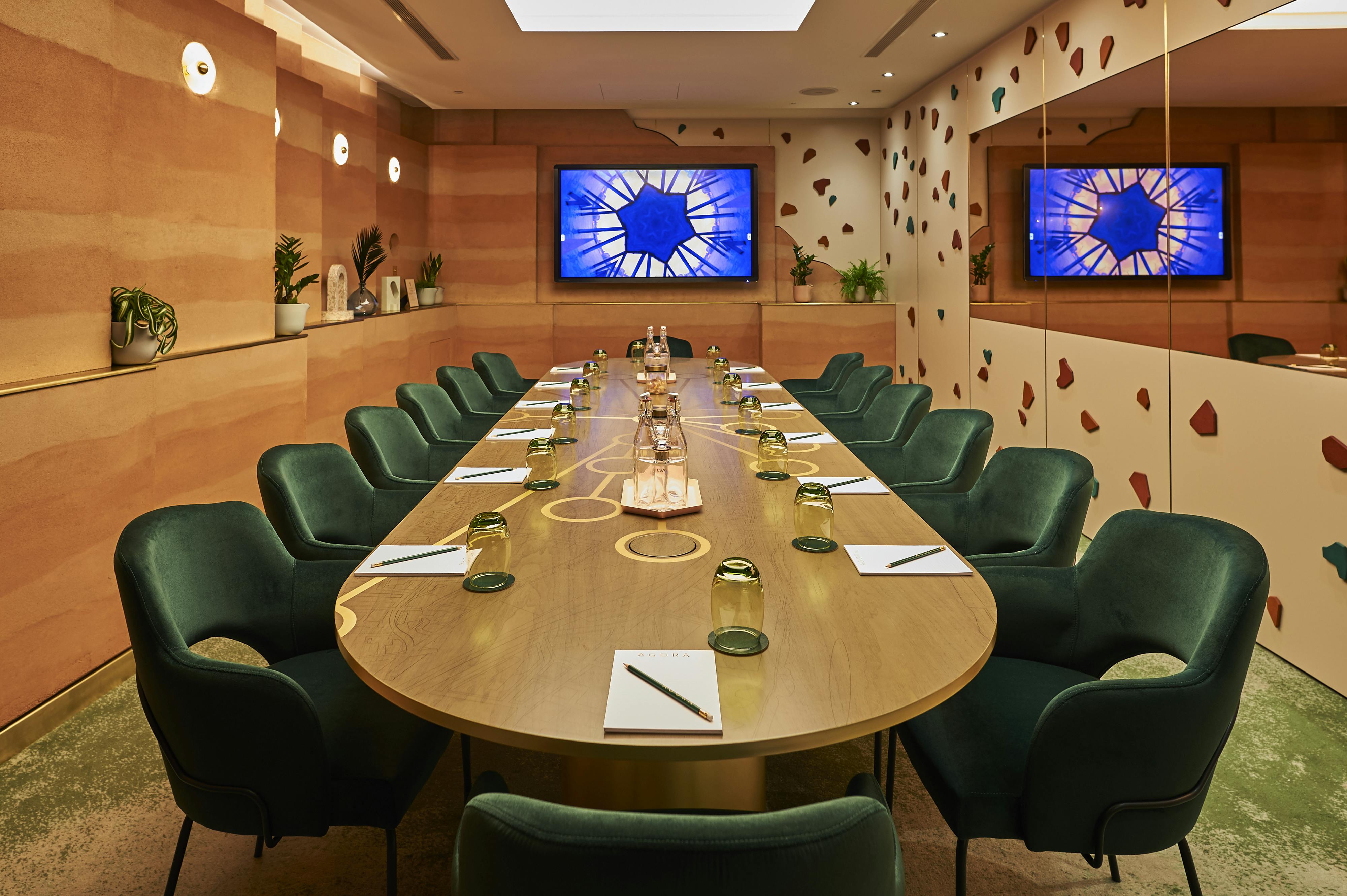 Modern meeting room at AGORA, Hilton London Bankside with oval table and green chairs.