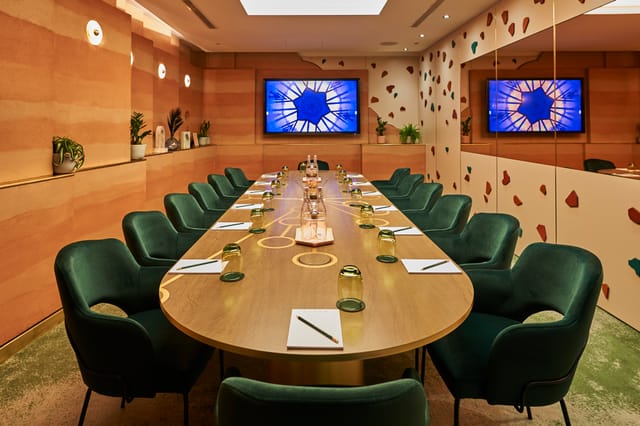 Modern meeting room at AGORA, Hilton London Bankside with oval table and green chairs.