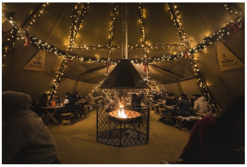 Cozy event space with string lights and fire pit for holiday parties and gatherings.